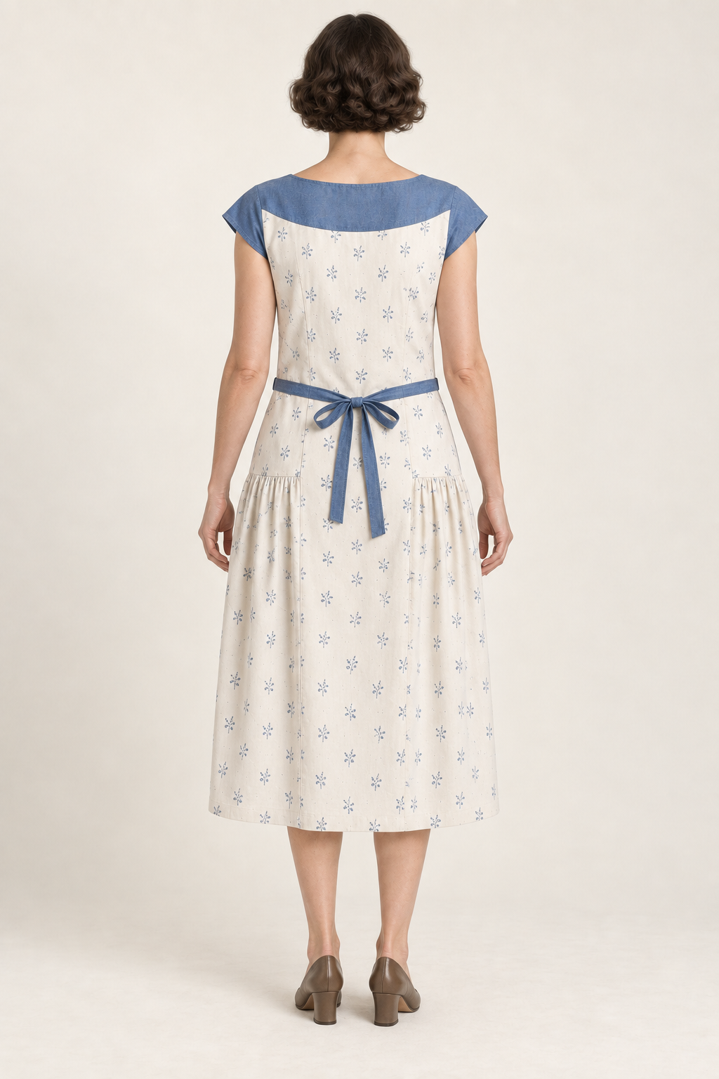 AI design illustration of the closed-back yoke apron dress showing the curved blue yoke and narrow back ties