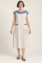 AI design illustration of a 1920s ivory yoke apron dress with blue sprigs, Delft-blue shoulder yoke and low side gathers, front view