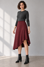 Three-quarter design preview of the oxblood woven skirt showing the curved left-knee rise and softly cascading hem