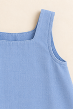 AI concept detail of the blue chambray sundress fixed shoulder strap, neckline and faced armhole