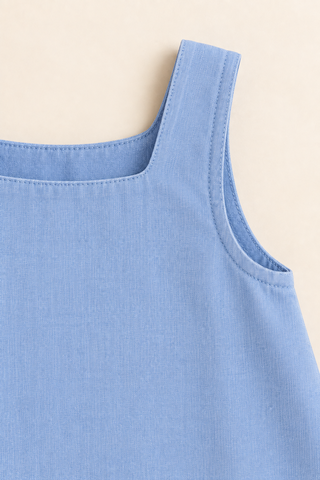 AI concept detail of the blue chambray sundress fixed shoulder strap, neckline and faced armhole