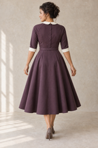 Rear design preview of the same aubergine raglan dress, showing five center-back bodice buttons, raglan joins and ivory cuff bands.