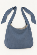 AI design preview: slate-blue shoulder bag untied to show two separate free strap ends and a curved open rim