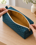 AI design preview: teal boxed zipper pouch held open to show one ochre-lined compartment with no internal pockets or dividers.
