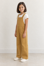 AI design preview: same child in ochre bib overalls, three-quarter view showing front pockets, button straps and planned left side opening
