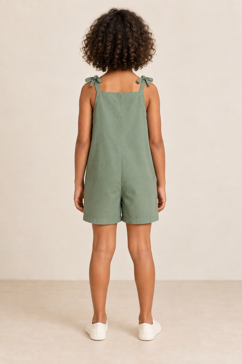 AI design preview: same child and eucalyptus romper, showing straight closed rear, shoulder bows and plain short legs without waist seam