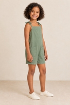 AI design preview: same child in eucalyptus pocket romper, three-quarter view showing compact shoulder ties and loose continuous side