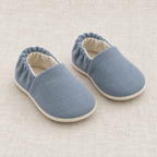 AI design preview: slate-blue soft baby shoes with rounded vamps, gathered elastic heels and cream lining, front view