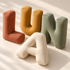 Close view of four stuffed alphabet letters with the ivory A showing its inner gusset and fabric seams
