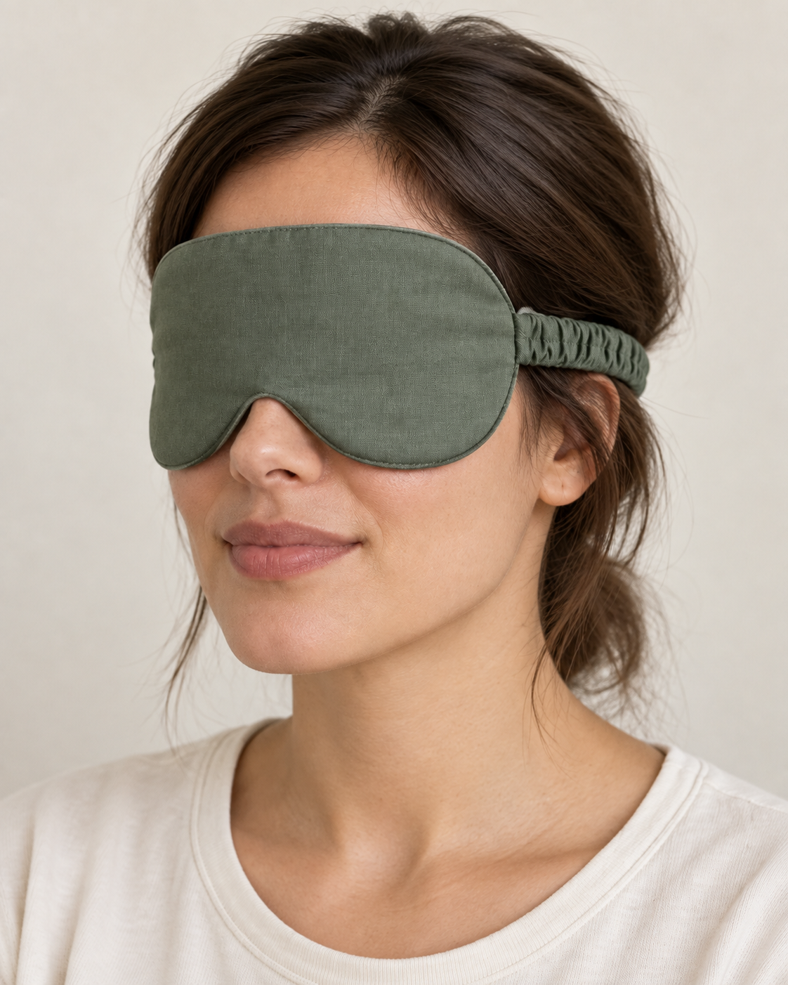 Design preview: same adult woman and sage green sleep mask from a side angle, showing the gathered elastic casing joined to the mask edge