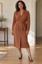 Adult woman wearing a cinnamon front-zip pleated dress with shawl collar and straight midi skirt