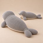 Rear view of the harbor seal plush showing the split rear flippers and curved back, with a smaller seal beside it