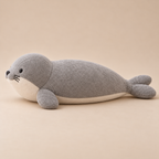 Side view of the gray harbor seal plush showing its ivory belly gusset, rounded front flipper and split rear flippers