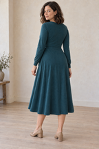 Rear three-quarter design preview of the same deep teal knit wrap dress, with a closed back, center seam and fitted jersey wristbands.