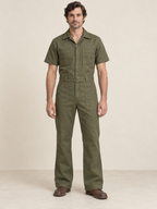 Man wearing an olive short-sleeve zip-front workwear jumpsuit with chest and thigh pockets
