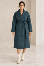 AI design preview: woman wearing a smoky teal quilted wrap coat with notched lapels, a front sash and slanted welt pockets.