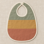 AI design preview: flat baby bib with sage, ochre and terracotta horizontal panels, ivory binding and one snap, front view