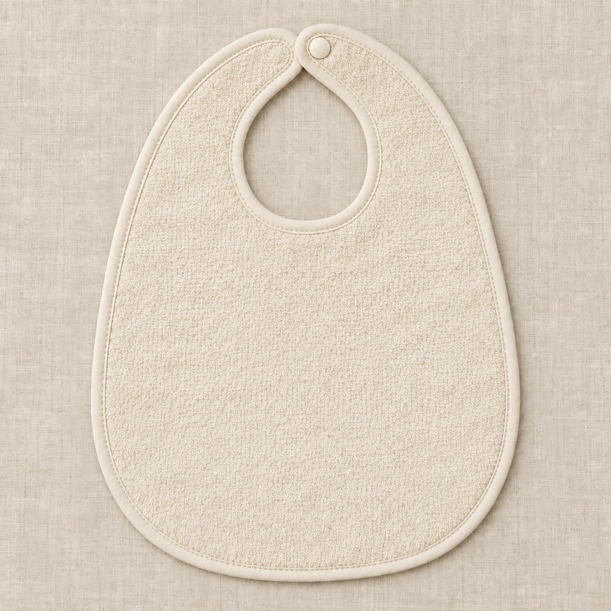 AI design preview: cream backing of the same rounded baby bib with bound neck opening and single snap, reverse view