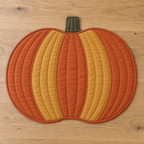 AI design preview: flat pumpkin placemat with five orange and ochre curved panels, olive stem and bound edge, front view