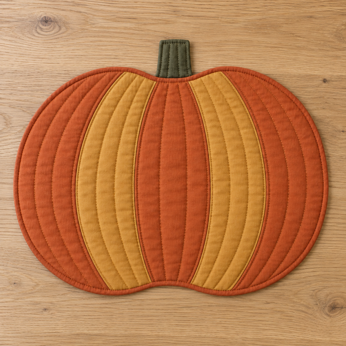 AI design preview: flat pumpkin placemat with five orange and ochre curved panels, olive stem and bound edge, front view