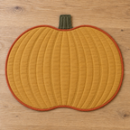 AI design preview: plain ochre reverse of the same pumpkin placemat with curved quilting and orange binding
