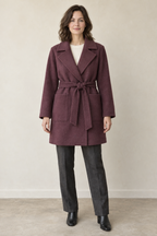 AI design preview: adult woman wearing a muted mulberry belted short wrap coat with broad notched lapels and two rectangular front patch pockets
