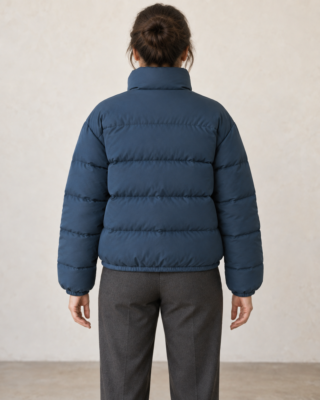 AI design preview: rear of the same puffer jacket on an adult woman, showing horizontal padded channels, high collar and elastic hem