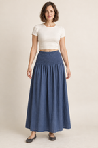 AI design preview: adult woman wearing a muted-indigo maxi skirt with a broad shirred hip yoke and one full gathered lower section, front view
