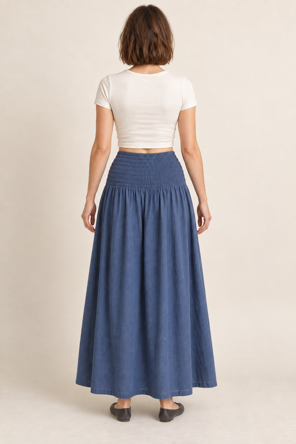 AI design preview: rear view of the same muted-indigo maxi skirt showing continuous shirring around the yoke and a plain closed ankle-length skirt