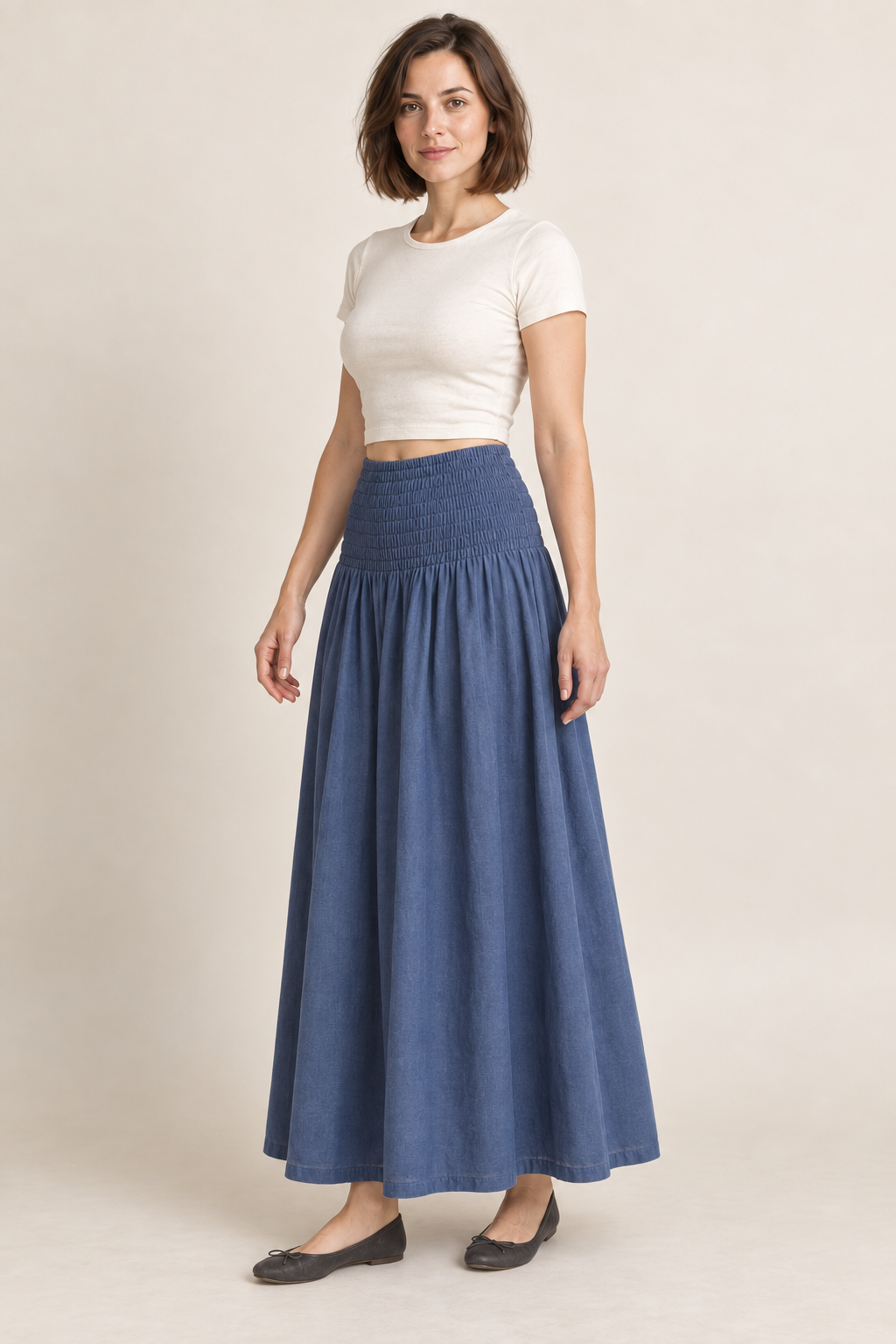 AI design preview: three-quarter view of the muted-indigo shirred-yoke maxi skirt showing the gathered joining seam and uninterrupted lower skirt