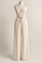 AI design preview: cream 1930s one-piece long pajama with blush neck tie, waist sash and V-mouth patch pockets.