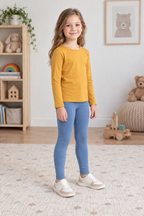 Three-quarter view of dusty-blue children's ankle-length leggings styled with an ochre long-sleeve top. Generated design preview.
