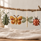 Four felt insect ornament designs hanging from cream thread loops on a natural branch.