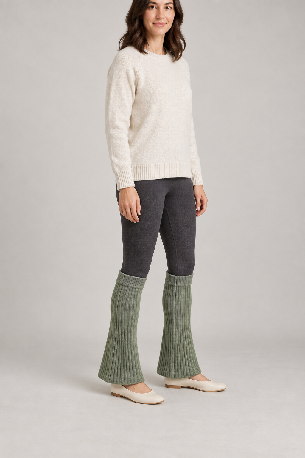 Three-quarter design preview of sage flared leg warmers worn over dark leggings.