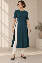 AI design preview: petrol teal knit tunic with waist-high side openings and narrow wrap ties, worn over ivory trousers