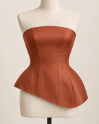 AI preview: copper-terracotta color option of the same panelled strapless top with a flared asymmetric hem.