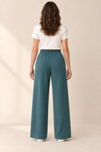 AI preview: rear of deep-teal knit wide-leg pants showing the gathered elastic waist, center-back seam and plain turned hems.