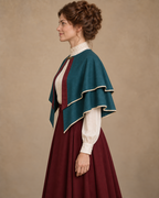 Side view of the peacock teal bolero cape with two curved ivory-trimmed hems