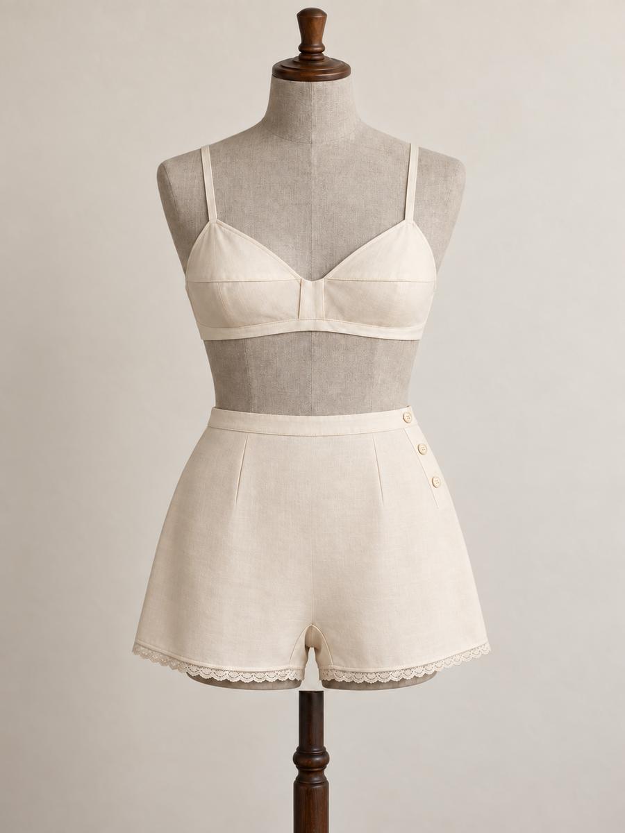 Front view of an ivory 1930s-inspired bra and tap pants set on a grey linen-covered fitting mannequin.