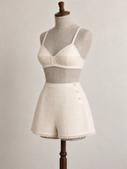 Three-quarter view of an ivory bra and high-waist tap pants set on a grey linen-covered fitting mannequin.