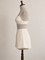 Left-side view of an ivory bra and side-button tap pants set on a grey linen-covered fitting mannequin.