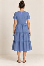 AI design preview: rear of the same blue tiered midi dress with a small keyhole, single button, waist darts and three skirt sections