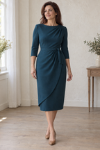 Adult woman wearing a deep petrol draped sheath with left shoulder pleats and curved front overlay