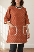 Round bound neck, below-elbow sleeve and pocket details of the rust smock apron