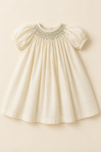 AI concept front view of an ivory bishop baby dress with sage neck smocking and short raglan sleeves