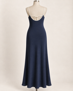 AI preview: ink-blue slip dress rear with a low U-shaped bound edge and a fine tie across the upper back.