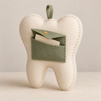 Angled view of the tooth fairy keepsake pillow with its envelope pocket open and a folded note inside