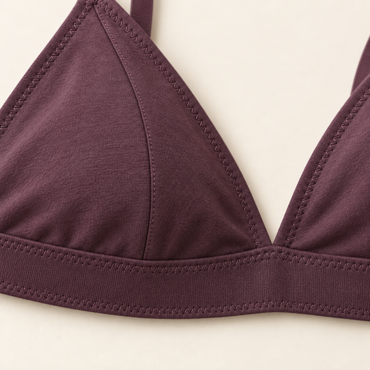 AI concept detail of a triangle cup seam meeting the plum bralette elastic underbust band