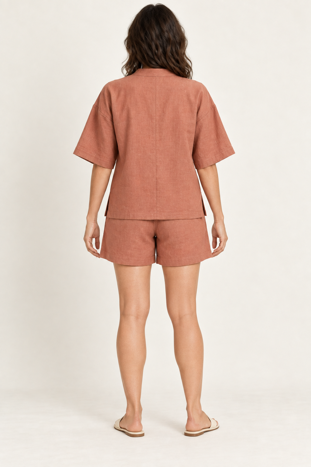 AI design preview: same woman and terracotta lounge set from behind, showing plain center-back top seam, elbow sleeves and loose shorts