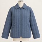 AI design preview: slate-blue zip-front quilted jacket with turnover collar, two slanted welt pockets, vertical quilting and bound edges